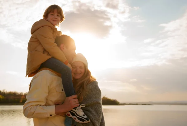 Familia em um passeio ao ar livre no fim de tarde, com uma criança no colo, transmitindo sensação de seguro contra acidentes em ambientes externos